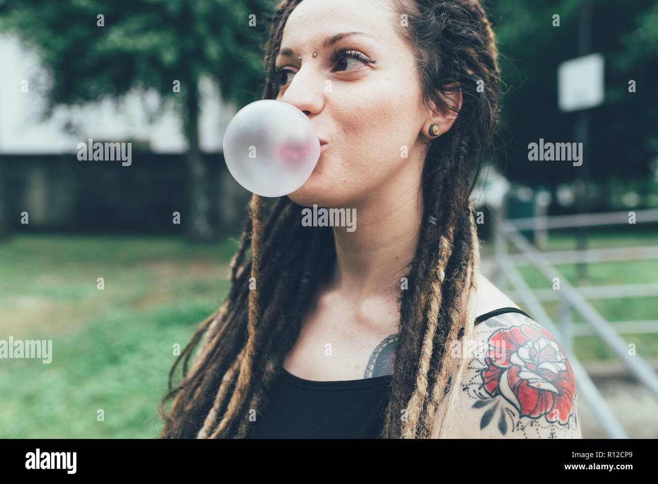 Frau blasen Bubble Gum in Park Stockfoto