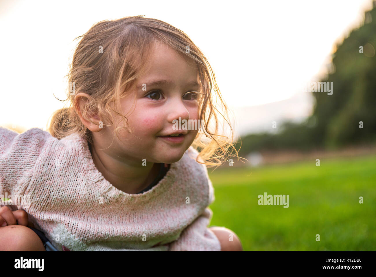 Kind sitzen auf Gras im Park Stockfoto