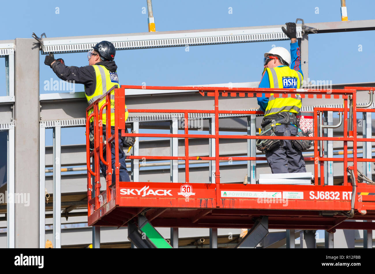 Männliche Arbeitnehmer in einem industriellen Skyjack Cherry Picker arbeitet auf einer Baustelle in Großbritannien. Stockfoto