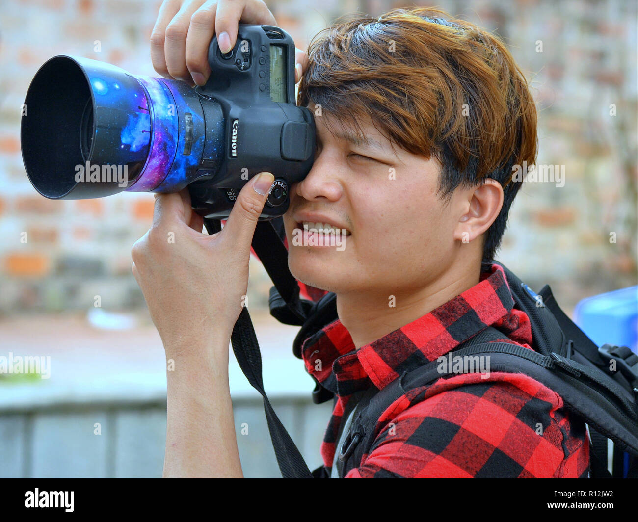 Junge vietnamesische Fotografin nimmt ein Foto im Hochformat mit einer Canon EOS 5D DSLR-Kamera. Stockfoto