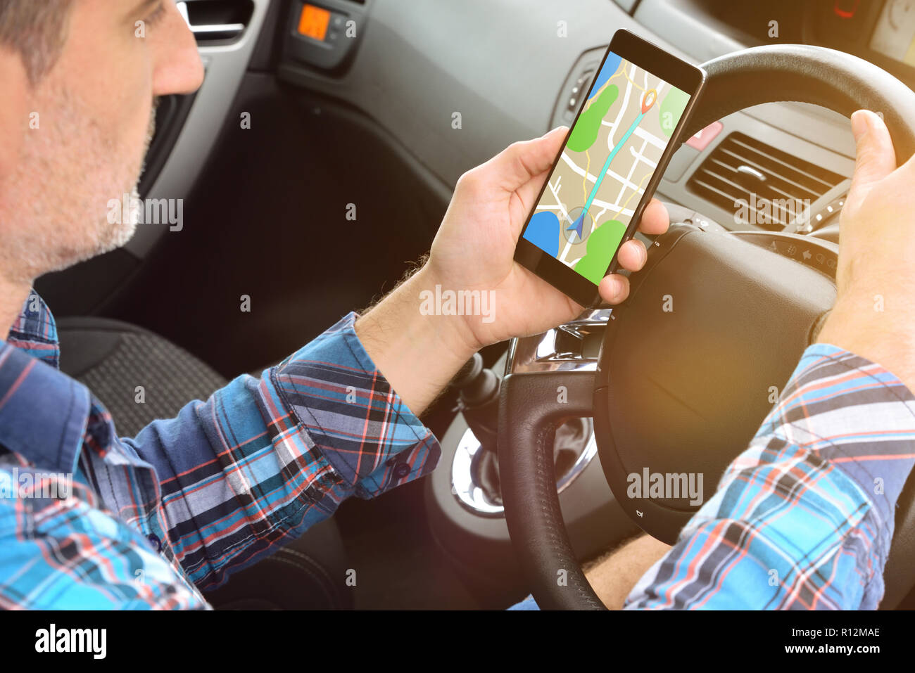 Mann Consulting eine Route auf ein Handy mit einer Anwendung sein Ziel mit dem Auto zu erreichen. Erhöhte Ansicht von hinten Stockfoto