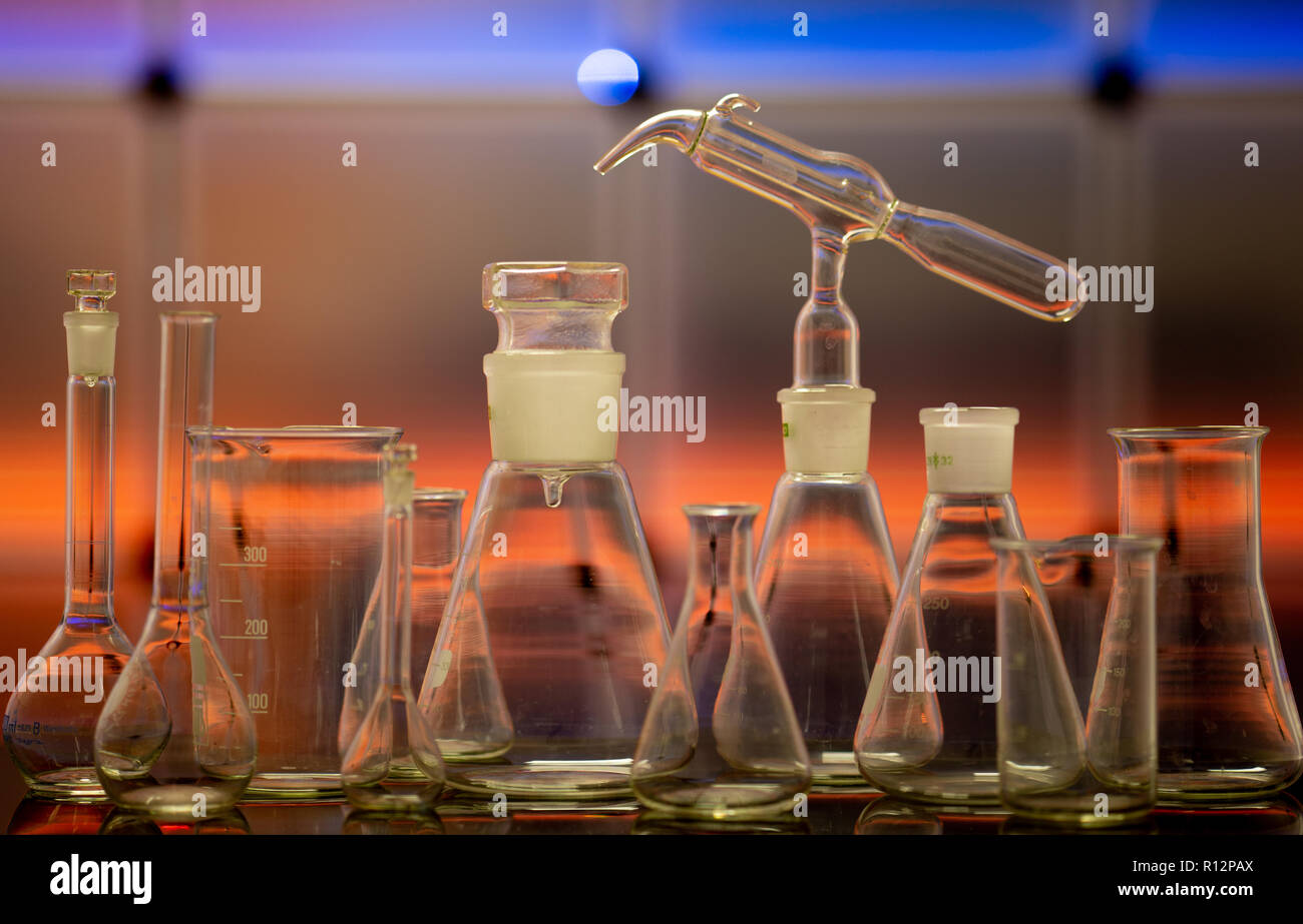 Leeren chemischen Glaswaren auf farbigen Hintergrund. Gruppe von Labor leeren Flaschen auf Farbe wissenschaftlichen Hintergrund Überlegungen zu einer Tabelle Stockfoto