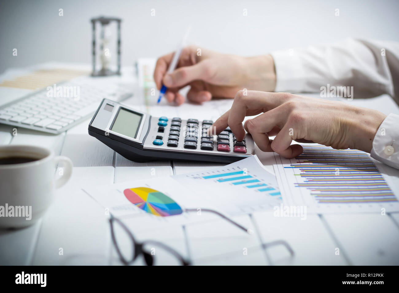 A business Person, ein Buchhalter, erstellt einen Finanzbericht mit einem Rechner während an einem Schreibtisch im Büro zu sitzen. Stockfoto