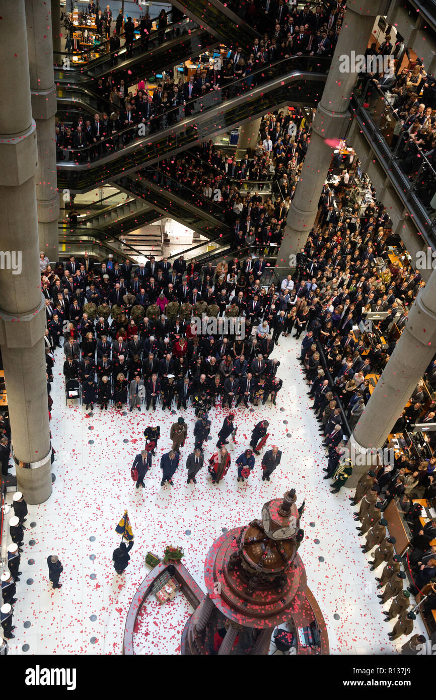 London, Großbritannien. 9. Nov 2018. Tausende Linie das Atrium und Fahrtreppen bei Lloyd's Gedenkstunde. Poppy Blütenblätter fallen von oben in die atriium als das Horn spielt "Die letzten Post". Die lutine Bell Sounds während der kranzniederlegung mit Würdenträgern einschließlich der Oberbürgermeister von London und Chelsea Rentner mit den 7 Gewehre, die den Schutz der Ehre Credit: Tommy London/Alamy leben Nachrichten Stockfoto