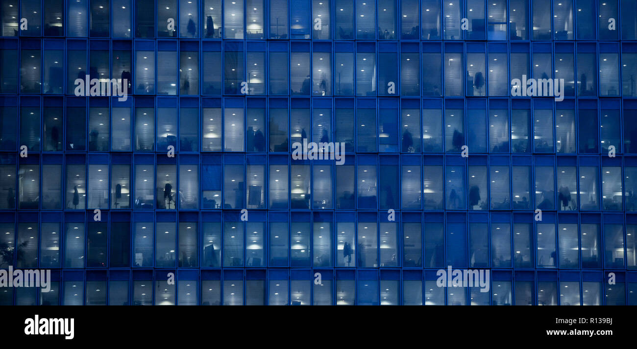 Blick auf Fenster mit Menschen bei der Arbeit im Inneren eines Bürogebäudes in der Nacht in Mailand, Italien am 8. November 2018. Stockfoto