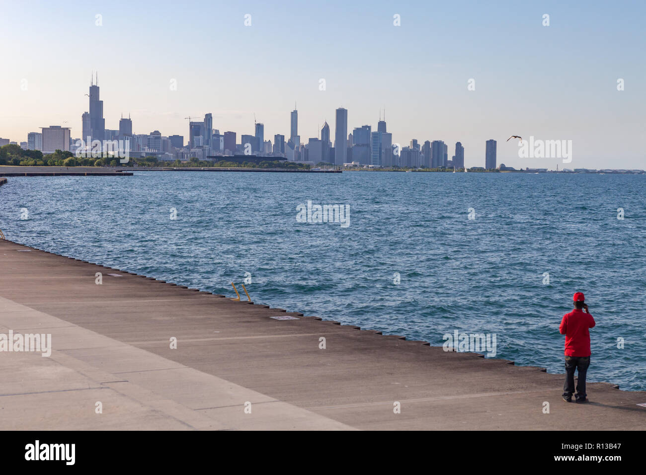 Blick auf die Skyline von Chicago mit der Person, die das Tragen der roten im Vordergrund, Schuß am Lake Michigan Waterfront, nördlich von Oakwood-41 st St. Strand an der Südseite. Stockfoto