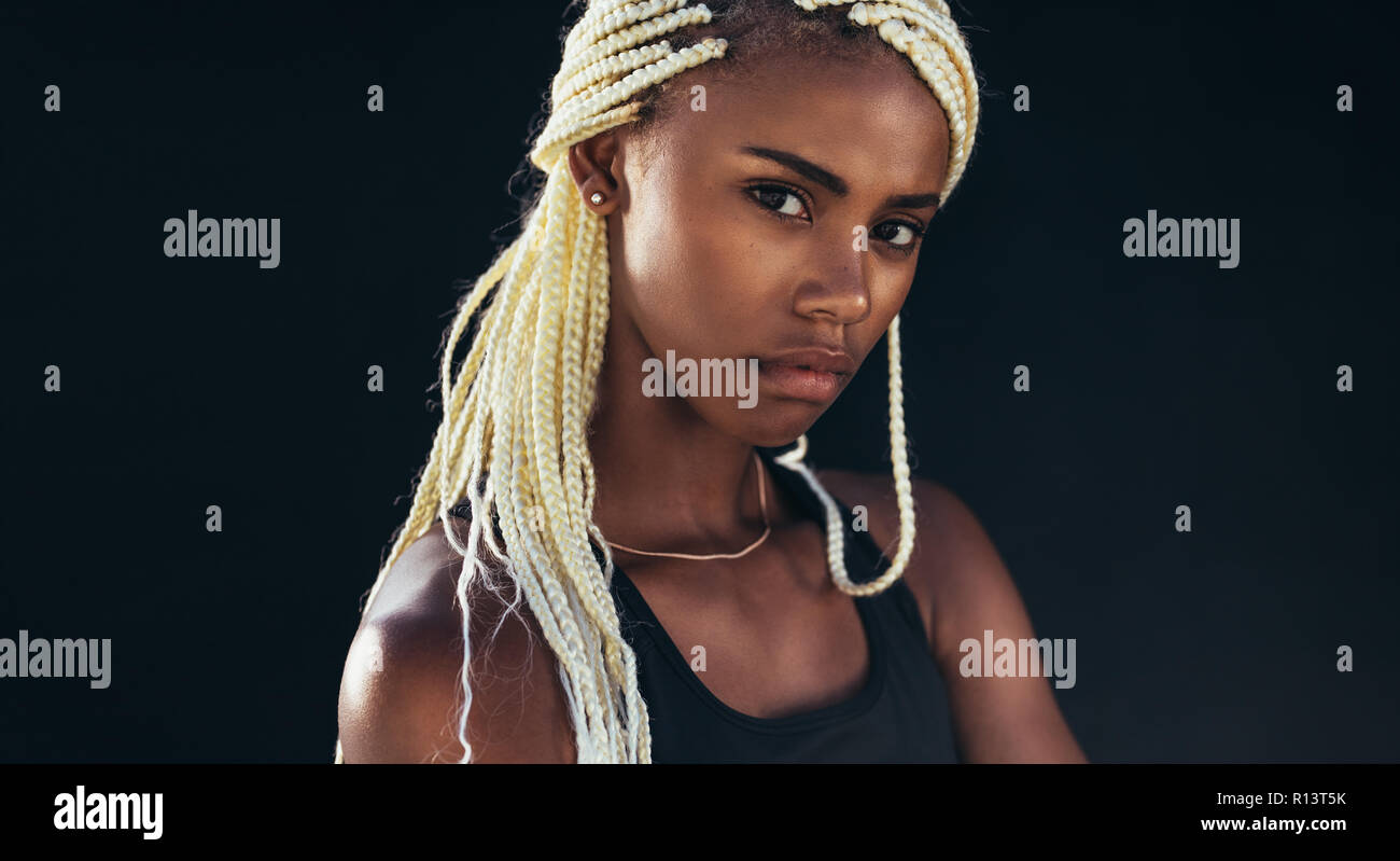 Nahaufnahme einer Sportlerin, die vor schwarzem Hintergrund steht. Fitness-Frau in Trainingskleidung. Stockfoto
