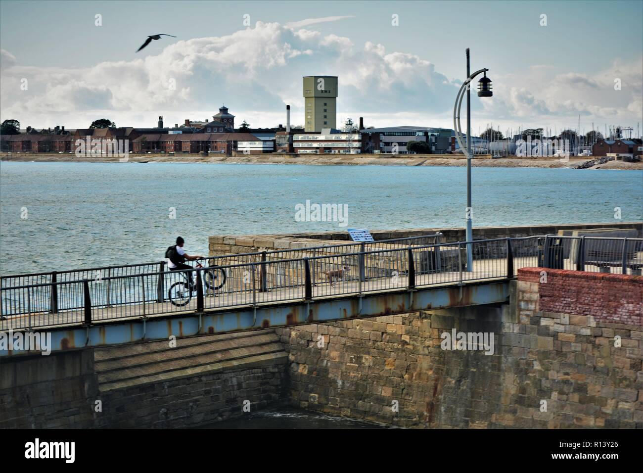 Ein Junge auf dem Fahrrad, der Wheelie fährt, während er auf der alten blauen Brücke von Portsmouth fährt und über den Eingang zum Hafen von Portsmouth schaut. 2018. Stockfoto