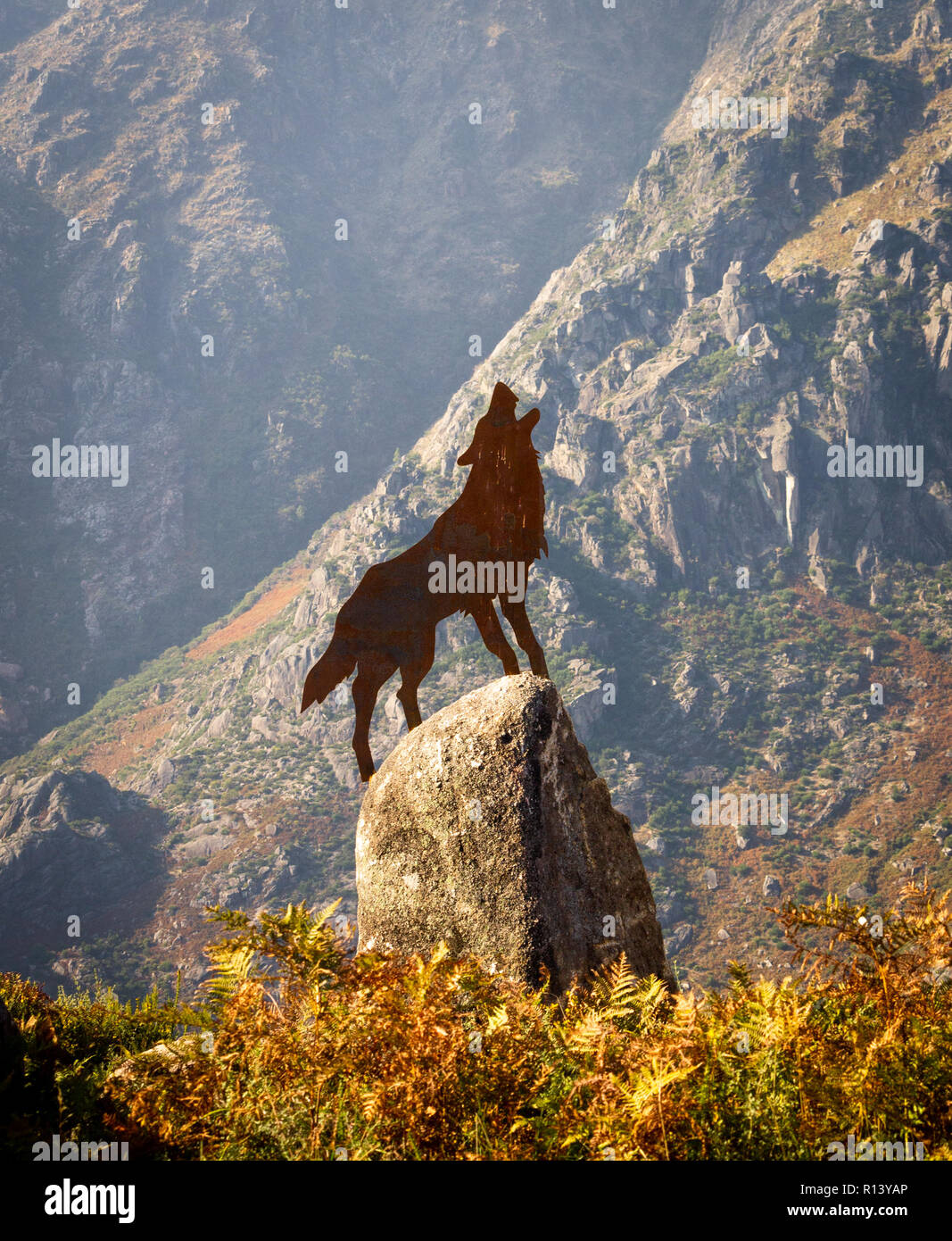 Messing Abbildung eines Wolfes auf einem Felsen zu heulen. Blätter im Herbst. Stockfoto