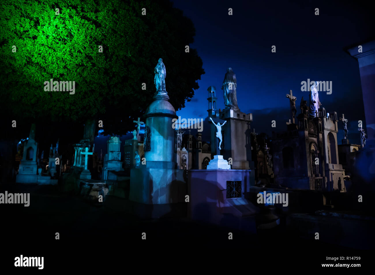 Dunkel Blau beleuchtet Grabsteine mit riesigen Baum während der Dämmerung in Cementerio General in Merida, Mexiko Stockfoto