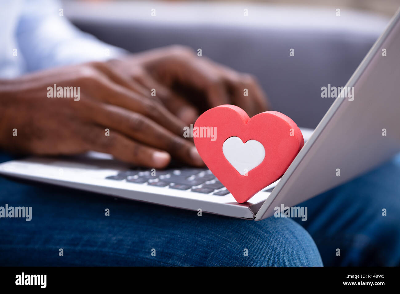 Nahaufnahme von roten Heartshape auf der Tastatur während des Menschen Hand mit Laptop Stockfoto