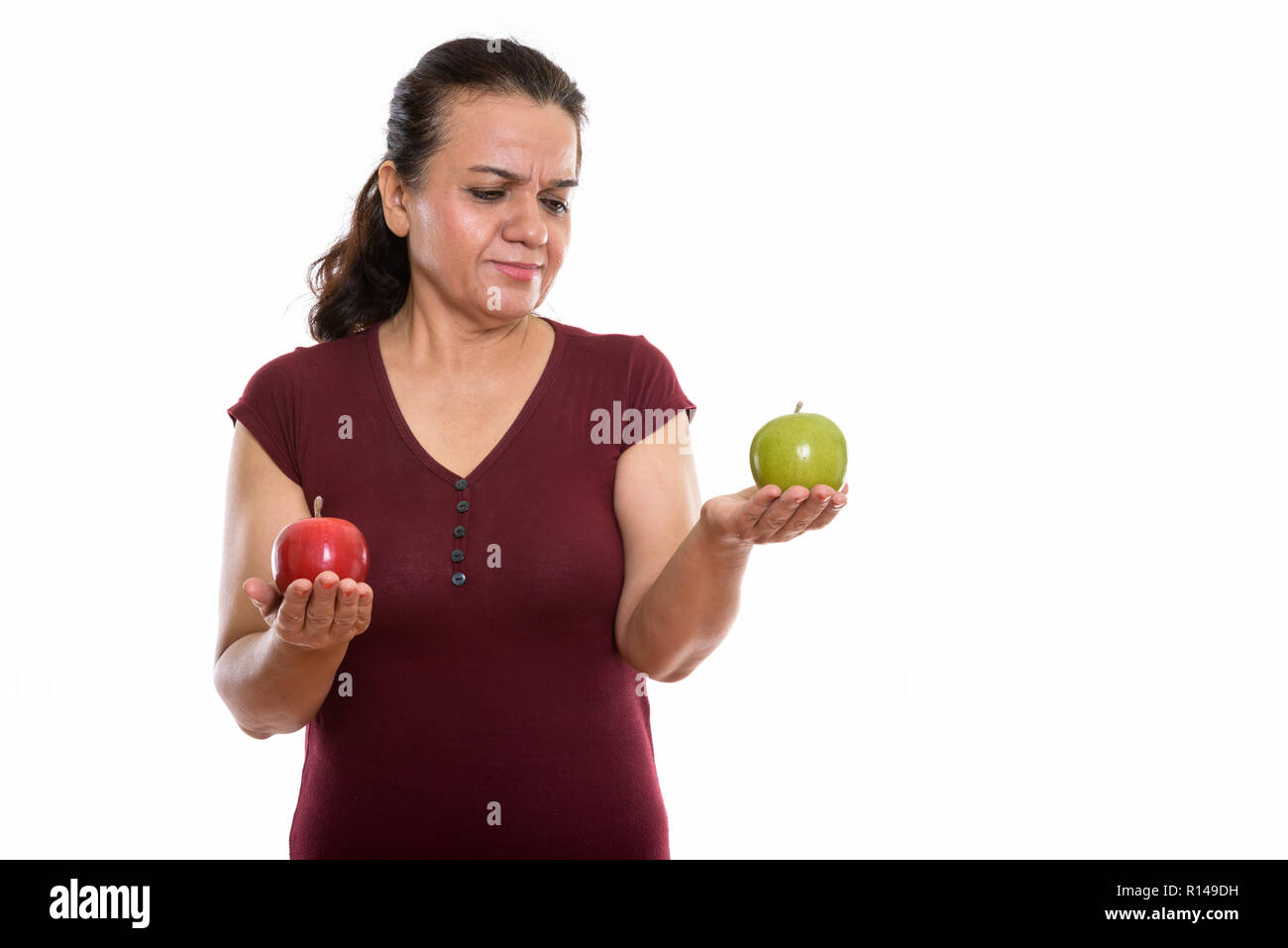 Studio shot reifer persische Frau mit roten Apfel, während Suchen Stockfoto