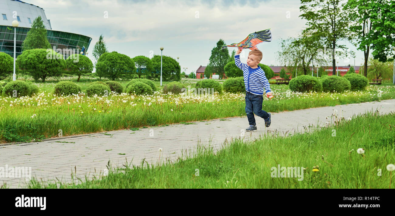 Little Boy über Park mit Drachen fliegen Spielzeug. Kaukasier Kind spielen auf Frühling. Freudige Lebensstil kid aktiv Erholung auf Straße. Tag im Sommer, im Freien. Kopieren Sie Platz für Text, Texthintergrund. Stockfoto
