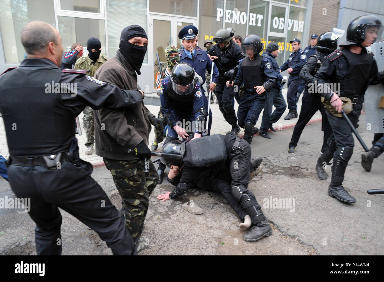 April 28, 2014 - Donezk, Ukraine: Eine ukrainische Bereitschaftspolizei officer Tauchgänge auf Pro-Ukraine Demonstrator, um ihn aus seiner pro-russischen Aggressoren zu schützen. Pro-Russia Kämpfer angegriffen Ukrainer, die friedlich für die Erhaltung der Einheit ihres Landes demonstriert. Die pro-russische separatistische Gruppe, meist Jugendliche in Balaclava, dann feierten ihren Aktionen durch schreien Sie hatten zertrümmerte 'Faschisten'. Une Manifestation pacifique en faveur de l'unite de l'Ukraine Donetsk est brutalement dispersee Gleichheit des Gruppen separatistes pro-Russes armes de Schlagstöcke et, pour Schneckaufkommen, armes d'b Stockfoto