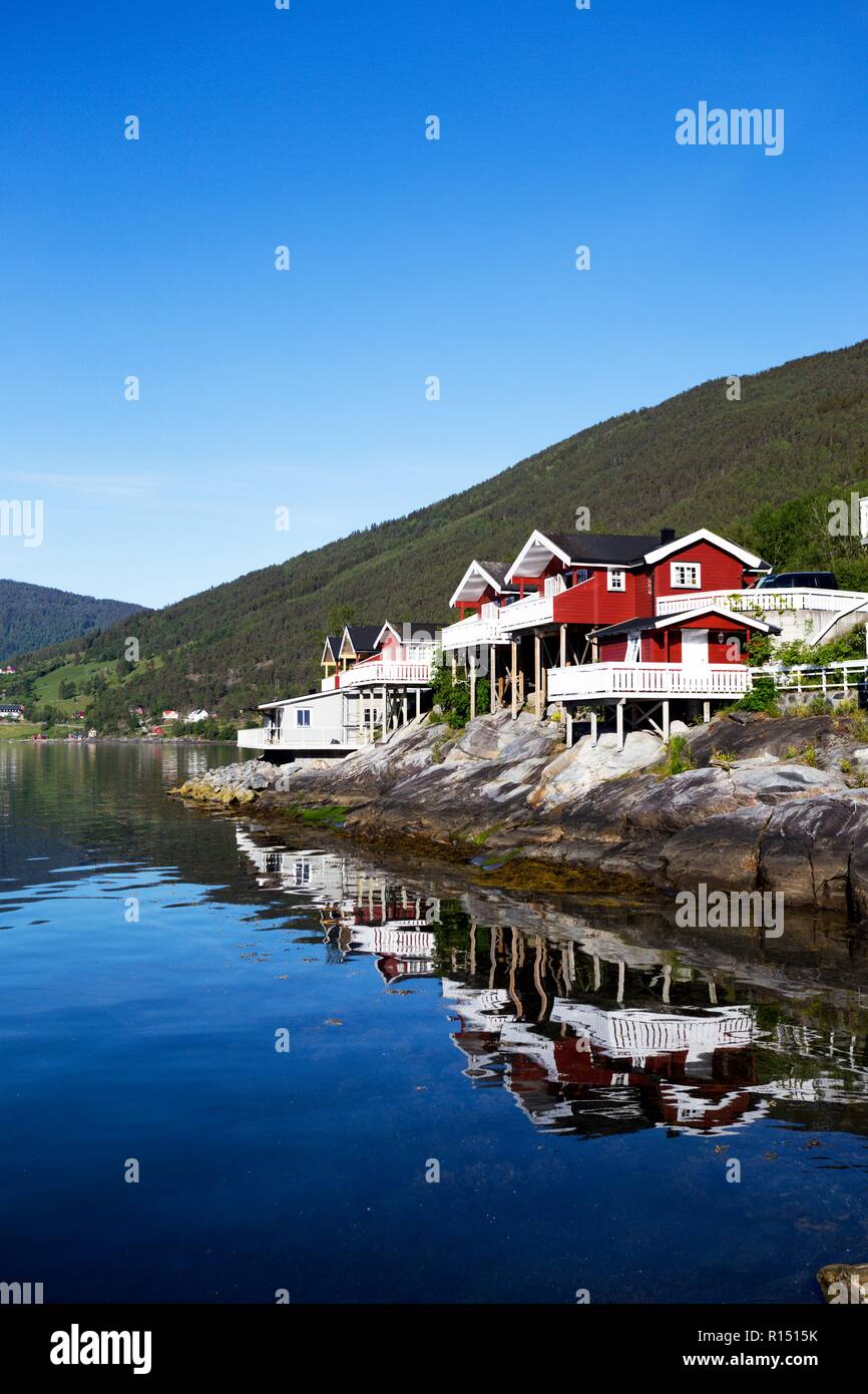 Rorbuer - traditionellen norwegischen roten Holzhaus am See und die Berge in der Ferne zu stehen, Norwegen Stockfoto