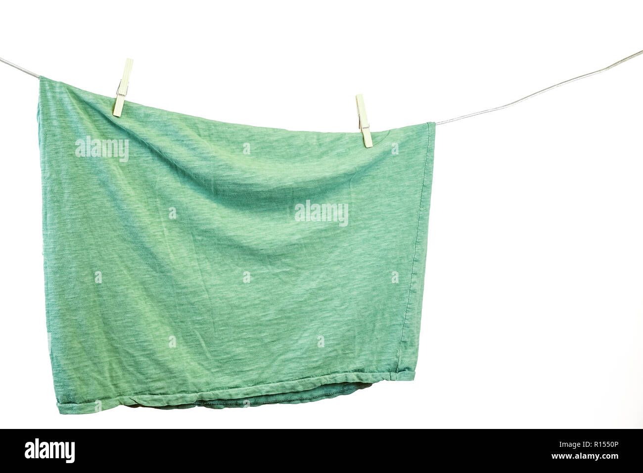 Grüne t-shirt hängen an einer Wäscheleine. Weißer Hintergrund. Stockfoto