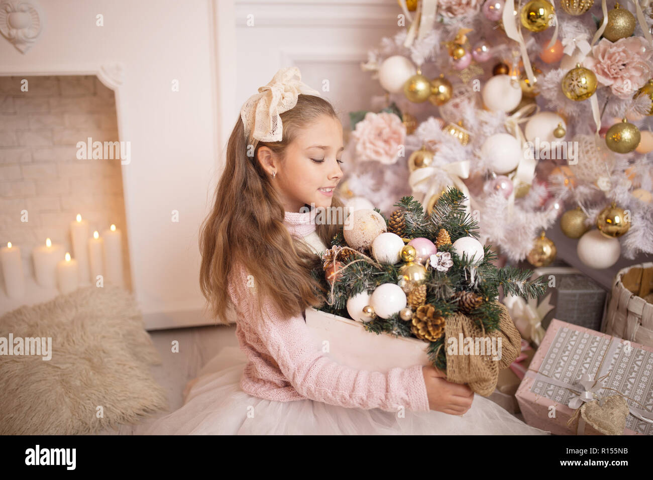 Frohe Weihnachten feiern. Schöne Mädchen in einem Kleid sitzt in der Nähe der Weihnachtsbaum. Winterurlaub. Frohes neues Jahr. Stockfoto