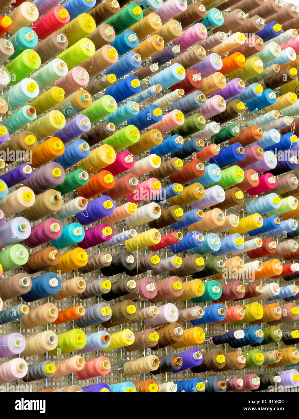 Organisierte Wand von Spulen mit Sewing Threads in vielen Farbvarianten Stockfoto