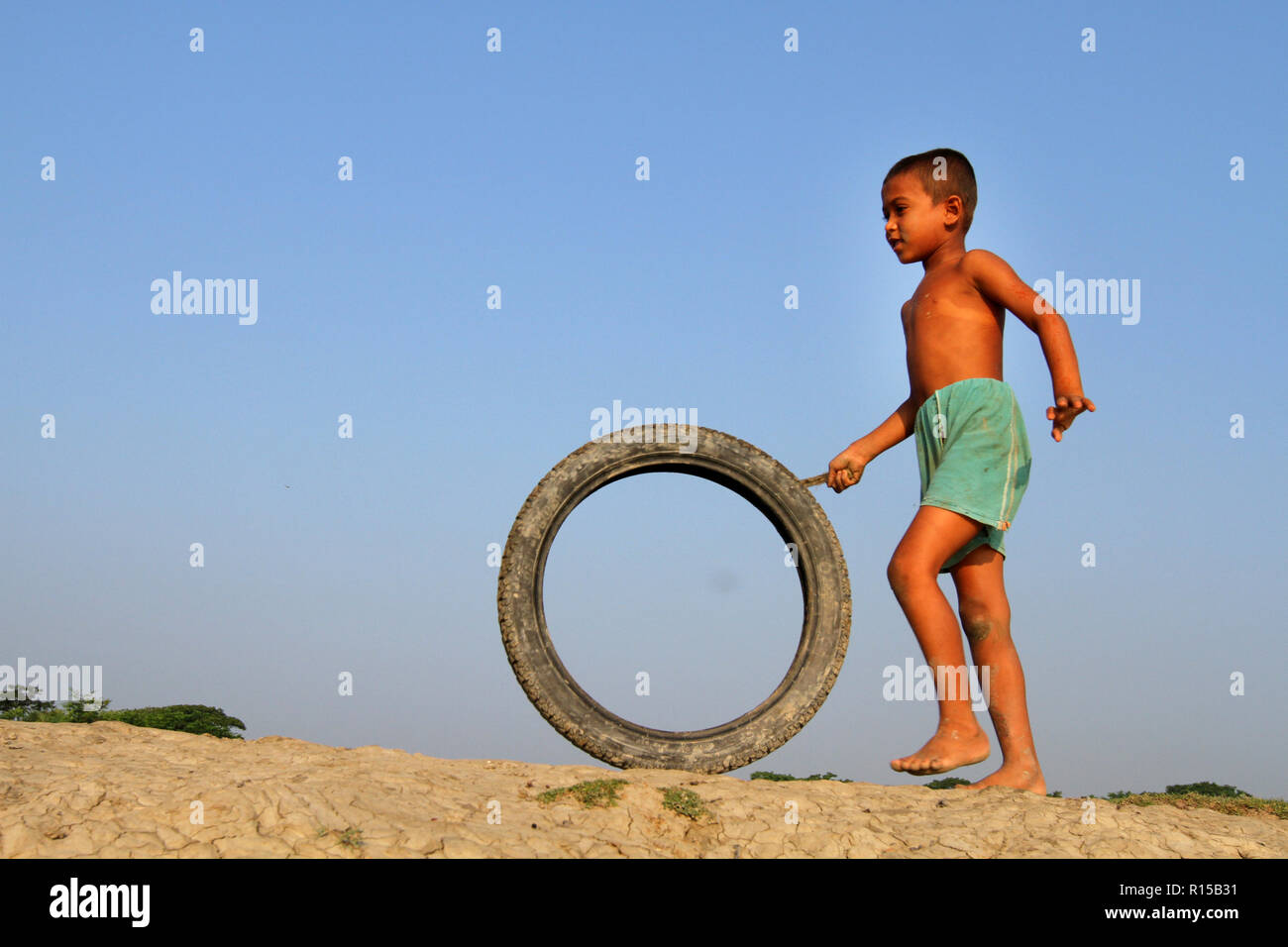 Khulna, Bangladesh - Oktober 08, 2014: Kinder spielen mit dem Fahrrad Reifen im Dorf das Feld bei Khulna, Bangladesh. Stockfoto