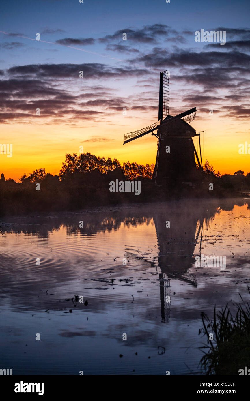 Silhouette einer Windmühle am warmen und rote Farbe Sonnenaufgang in Hazerswoude-Dorp Dorf, Niederlande Stockfoto