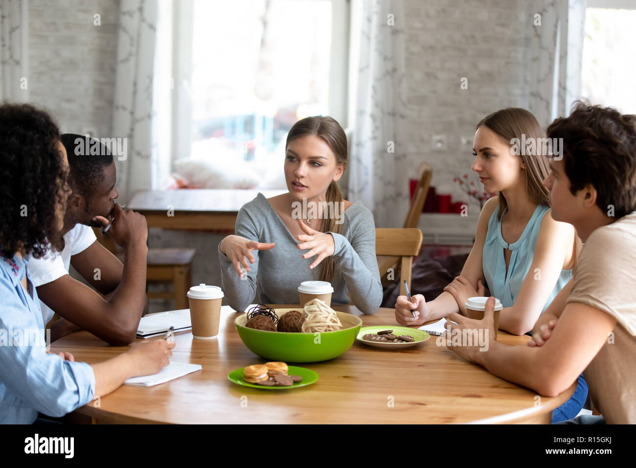 Vielfältigen, multi-ethnischen Studenten sitzen um Kreis Tabelle Schulfreund Ideen zusammen studieren in Cafe hören. Multirassischen beste Freunde versammelt togethe Stockfoto