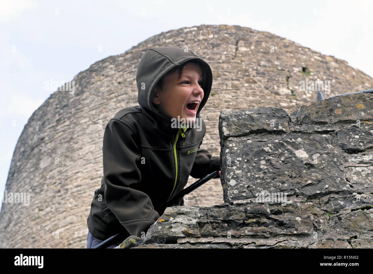 Ein Kind, das schreiend über den Rand einer Burgmauer im Dinefwr Castle im Dinefwr Park Llandeilo, Carmarthenshire, South Wales, Großbritannien, GELEHNT IST, KATHY DEWITT Stockfoto