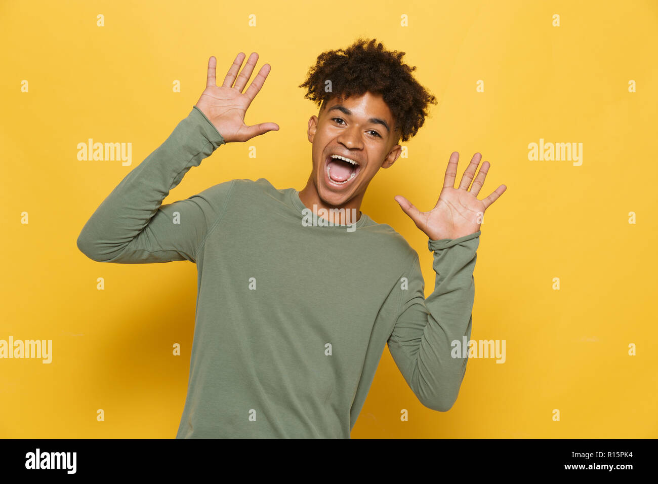 Portrait von fröhlichen dunkelhäutige Kerl in stilvollen afro Frisur schreien oder Aufruf über Gelb Hintergrund isoliert Stockfoto