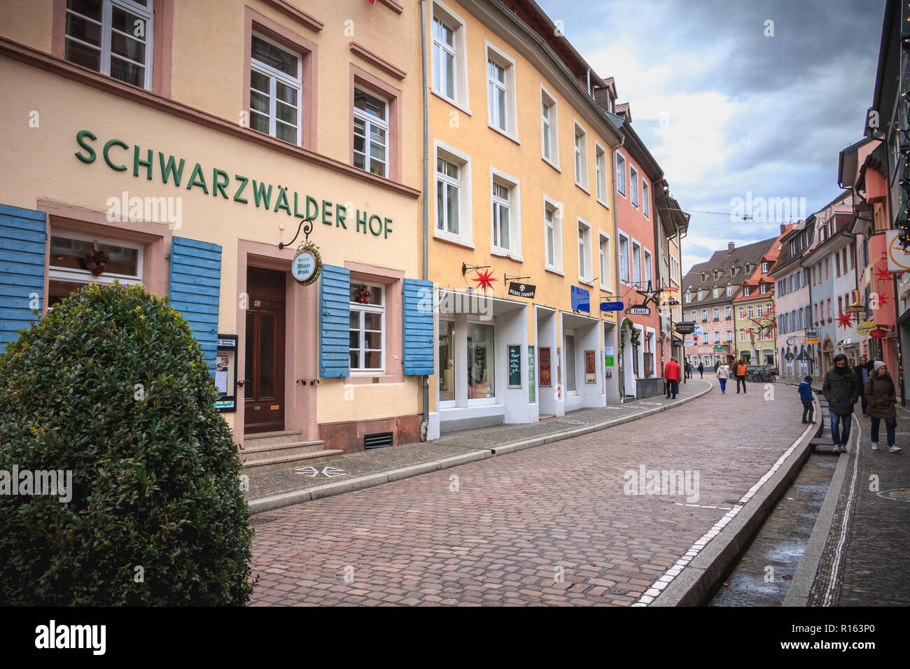 Freiburg im Breisgau, Deutschland - 31. Dezember 2017: Menschen zu Fuß auf einer kleinen Straße mit Kopfsteinpflaster mit typischen Architektur Häuser in der historischen Stadt Stockfoto