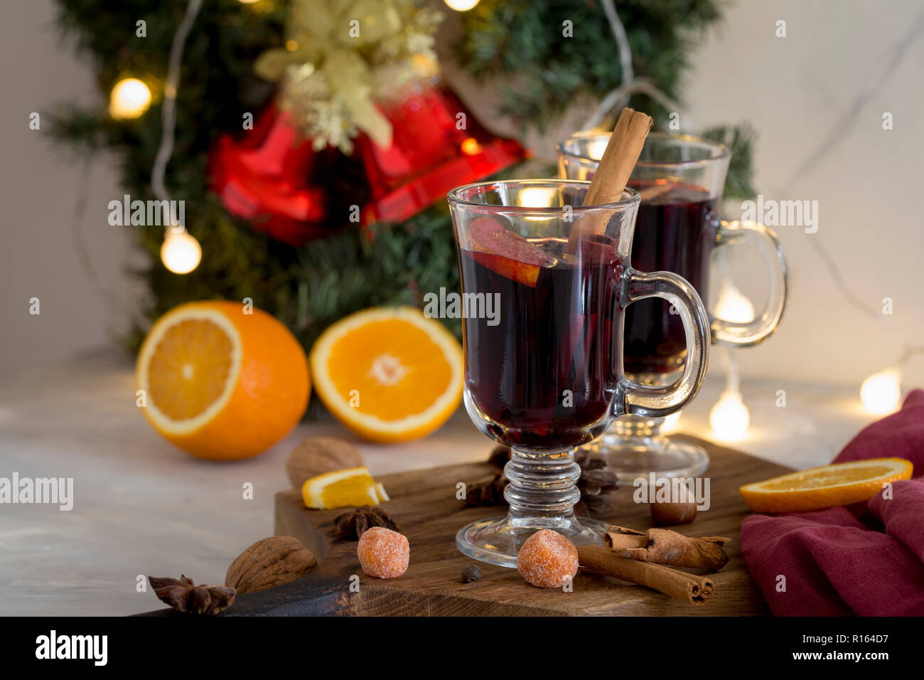 Winter Zusammensetzung. Glühwein in Gläsern auf Holz Board auf weißen Hintergrund. Tanne Kranz, Glocken, Lametta und Girlanden, Orange, Zimt und Gewürze in der Nähe von Stockfoto