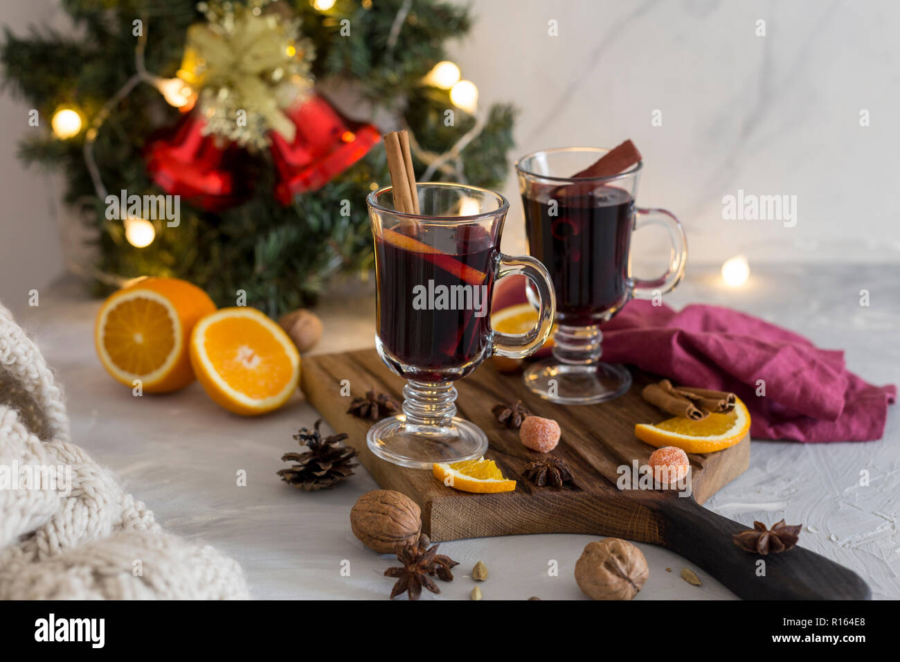 Winter Zusammensetzung. Glühwein in Gläsern auf Holz Board auf weißen Hintergrund. Tanne Kranz, Glocken, Lametta und Girlanden, Serviette, Orange, Zimt und Spi Stockfoto