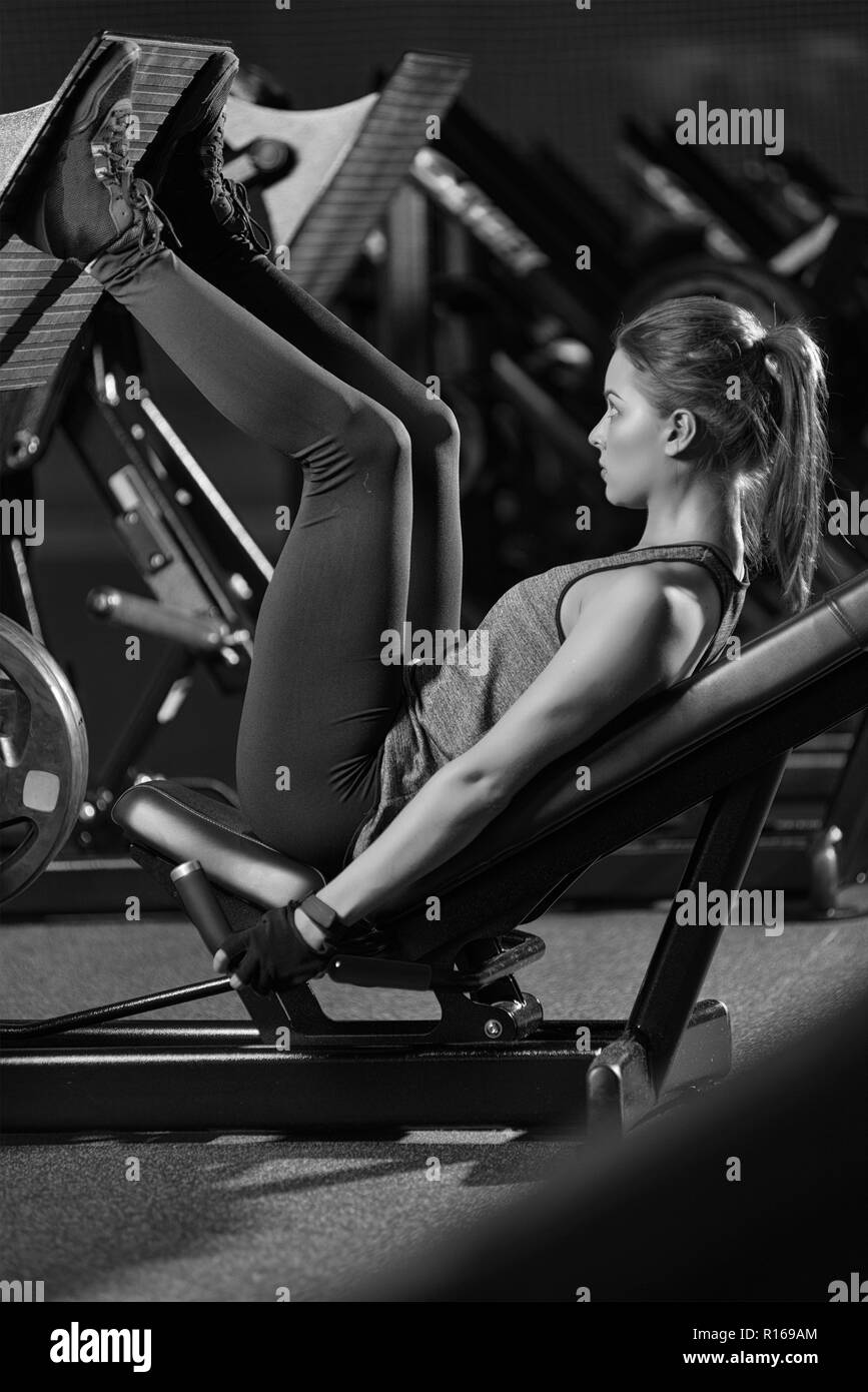 Sportliche Frau mit Gewichten-Presse-Maschine für die Beine. Fitness-Studio. Stockfoto