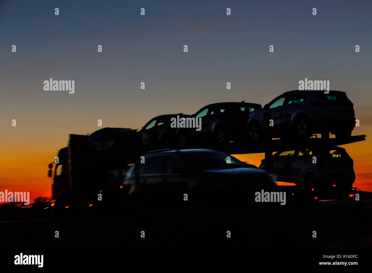 Lkw Transport von neuen Autos auf der Autobahn am Abend bei Sonnenuntergang Stockfoto