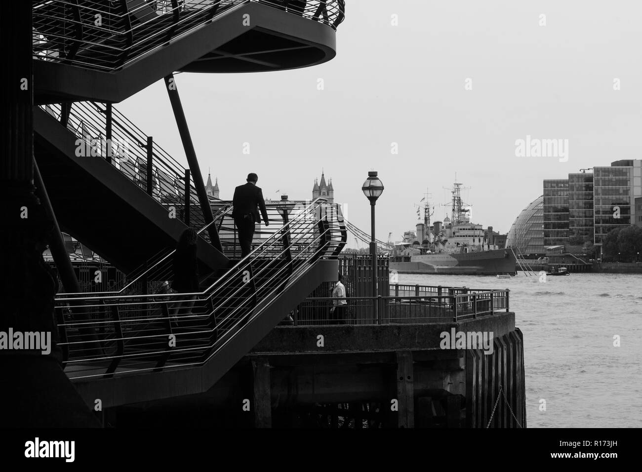 Stadtarbeiter die Treppen zur London Bridge, mit HMS Belfast und London und City Hall in der Ferne Stockfoto