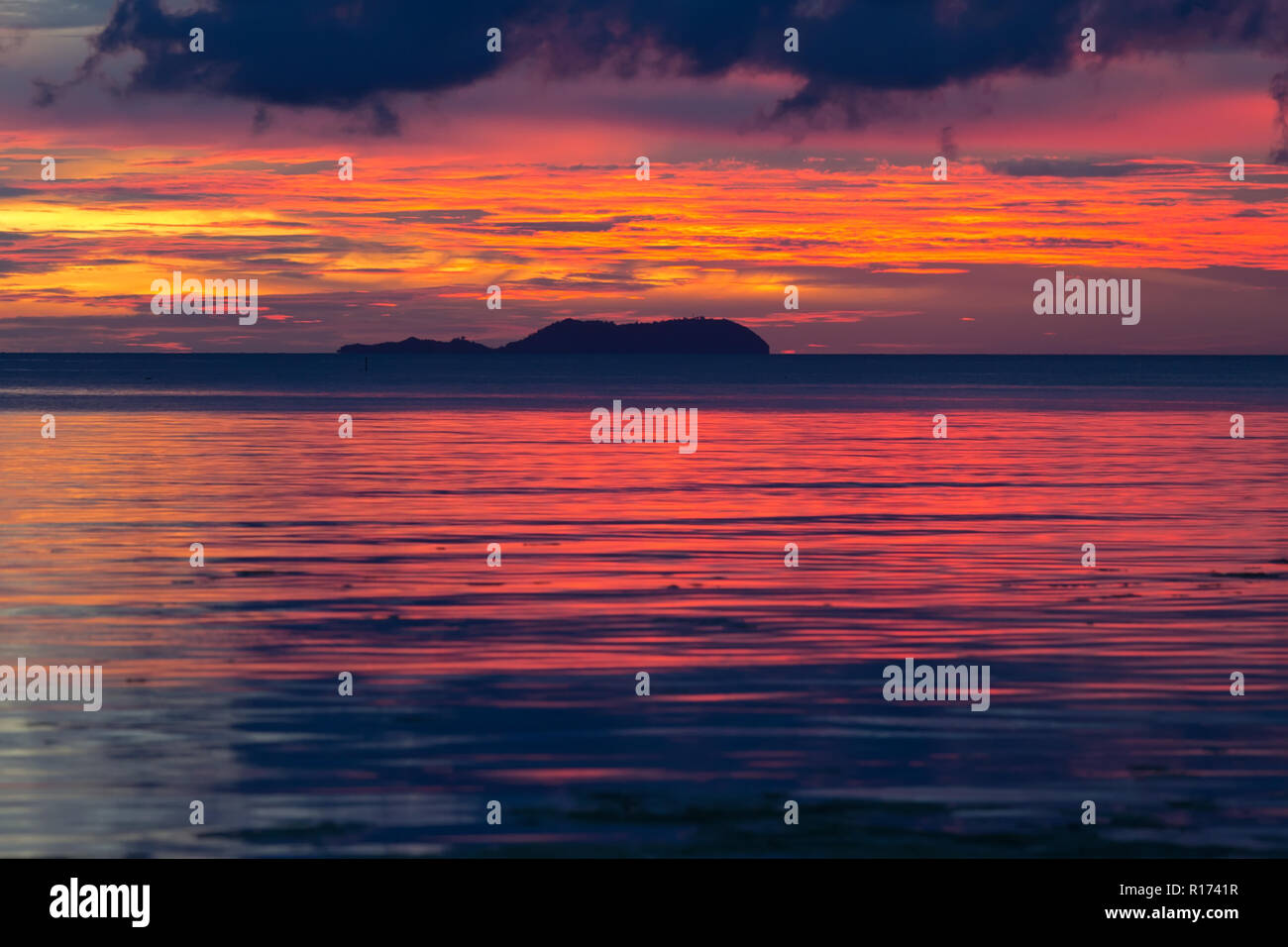 Dramatische Fiery orange und rot Sonnenuntergang in Siquijor auf den Philippinen mit einem Mangrove Tree gegen den leuchtenden Horizont unter schwerem Sturm cl Silhouette Stockfoto