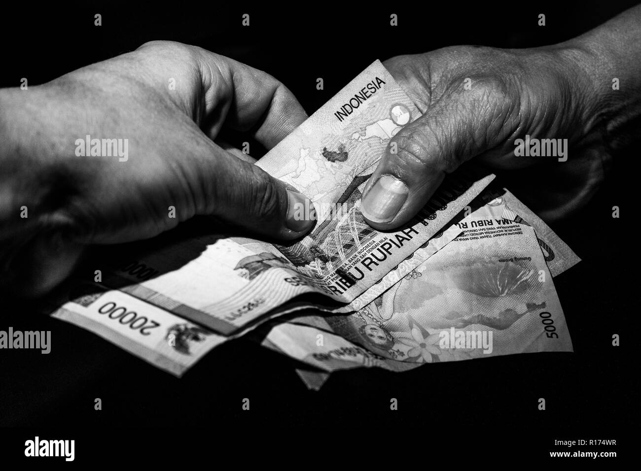 Zwei Hände, ein indonesischer und eines der kaukasischen weißen Übergabe indonesischen Banknoten zu einander. Konzept der Business beschäftigen. Stockfoto