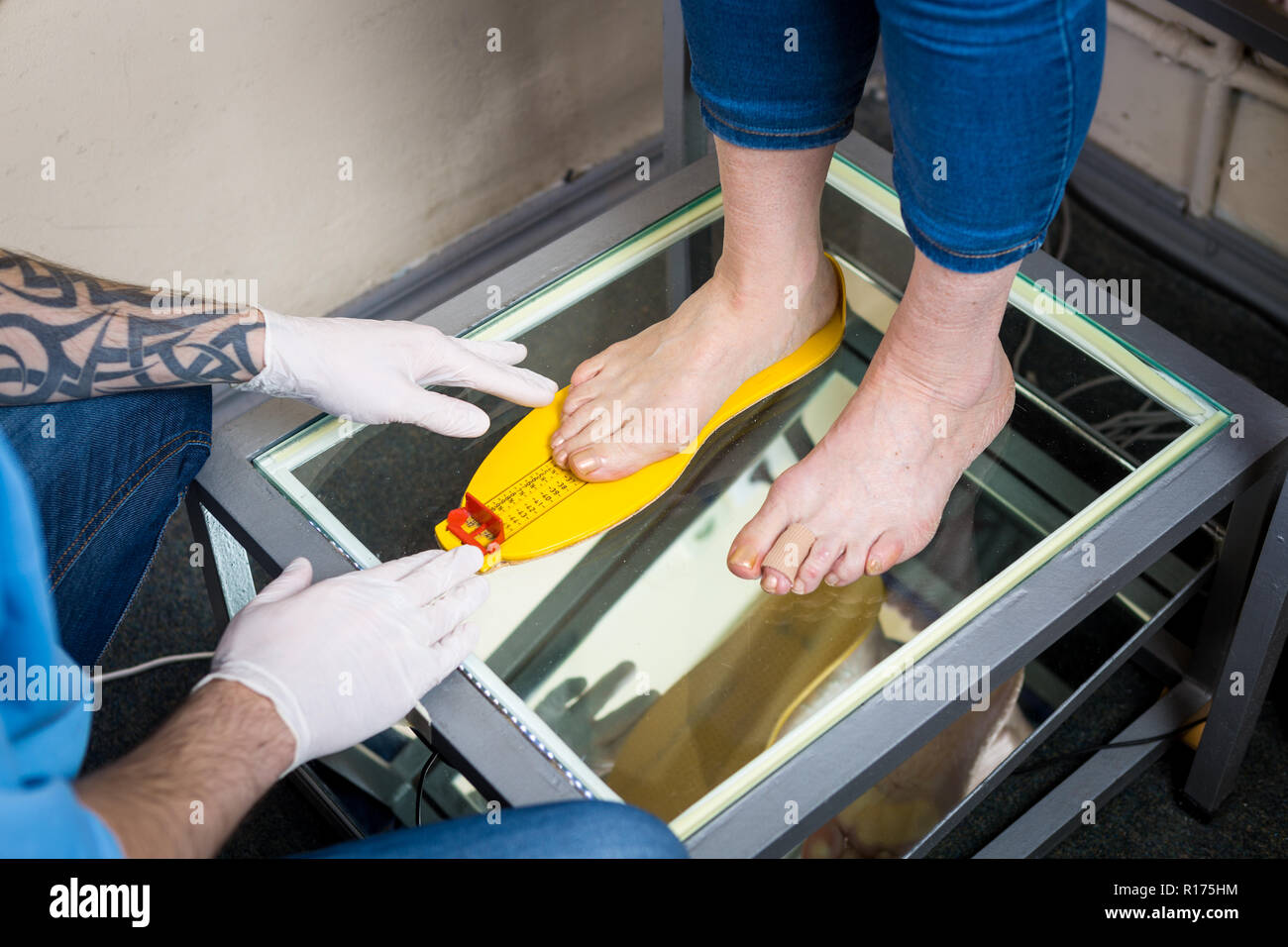 Orthopädie und Medizin. Junge kaukasier Arzt Hände Mann tattoo Latex Handschuhe Größe Messung Form des Fußes für die Herstellung von Einzelnen oder Stockfoto