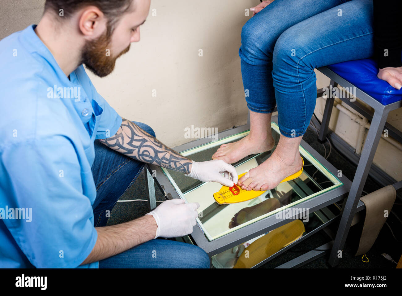 Orthopädie und Medizin. Junge kaukasier Arzt Hände Mann tattoo Latex Handschuhe Größe Messung Form des Fußes für die Herstellung von Einzelnen oder Stockfoto