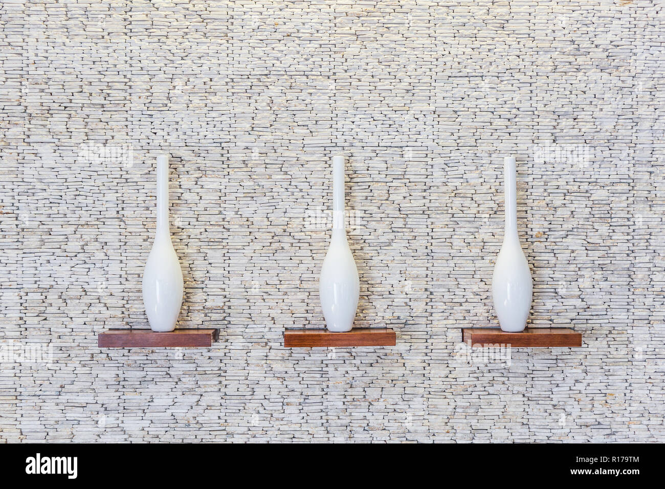 Dekorative Vasen auf holzregal am weißen Stein Textur Hintergrund Stockfoto