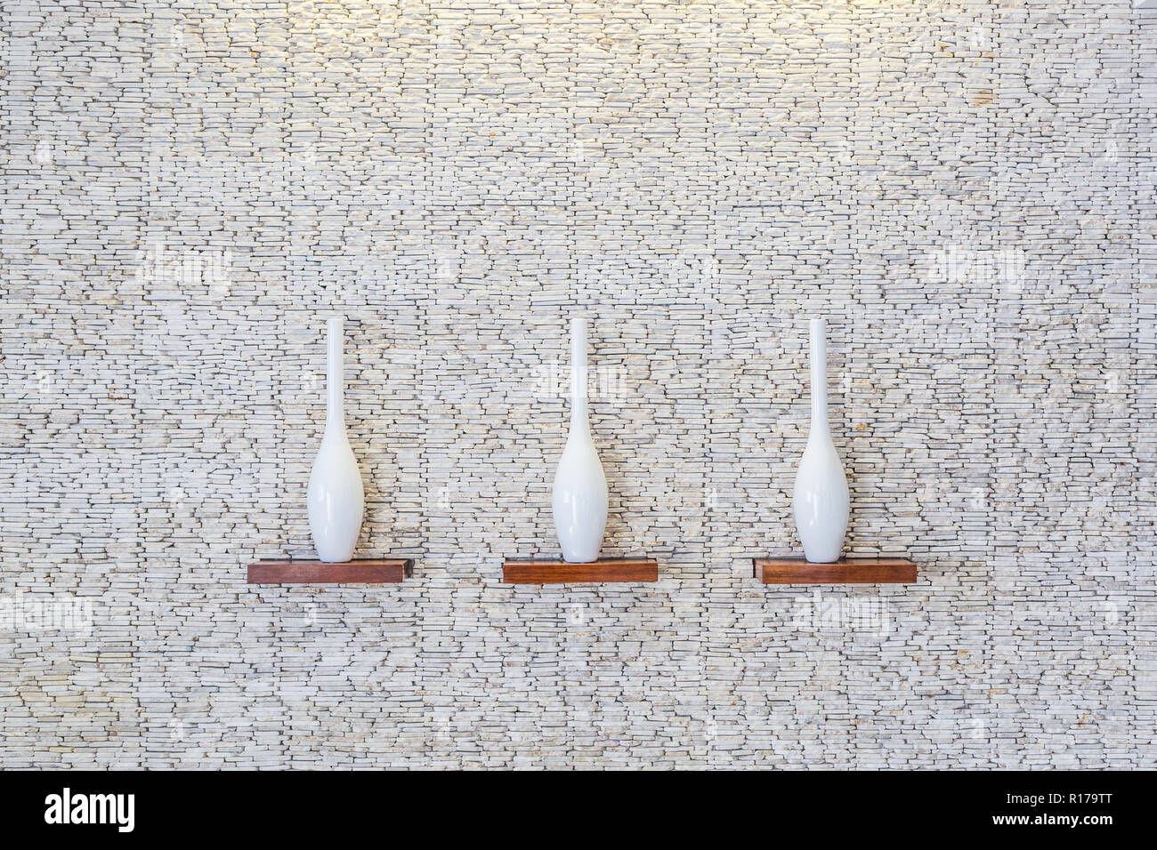 Dekorative Vasen auf holzregal am weißen Stein Textur Hintergrund Stockfoto
