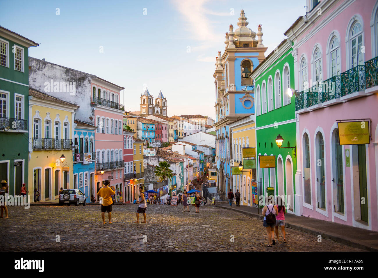 SALVADOR, BRASILIEN - ca. März 2018: Touristen nehmen Bilder der bunten kolonialen Architektur entlang der gepflasterten Hügel von Pelourinho. Stockfoto