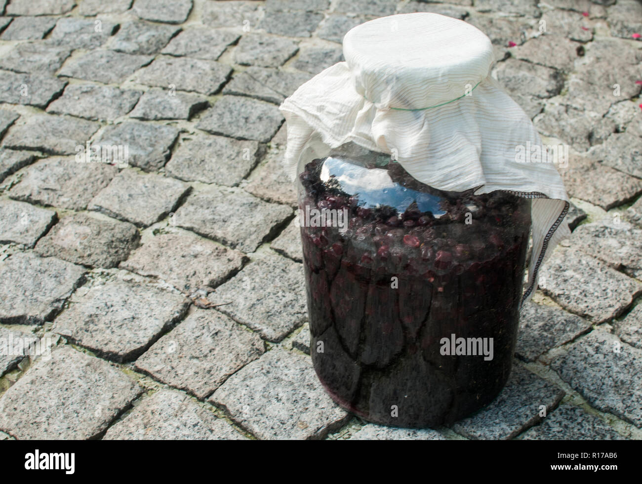 Großes Glas Glas mit Zucker getränkten Sauerkirschen und Alkohol Gärung für die hausgemachten Likör closeup auf Haus Hinterhof Stockfoto