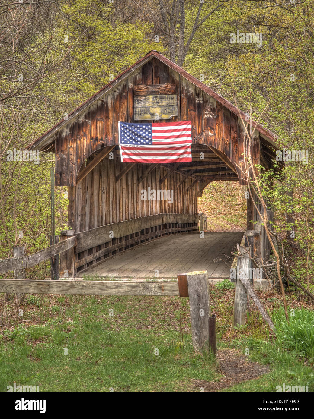 Eine verlassene Brücke stolz fliegen die amerikanische Flagge auf dem verwitterten Holz Design im frühen Herbst. Stockfoto