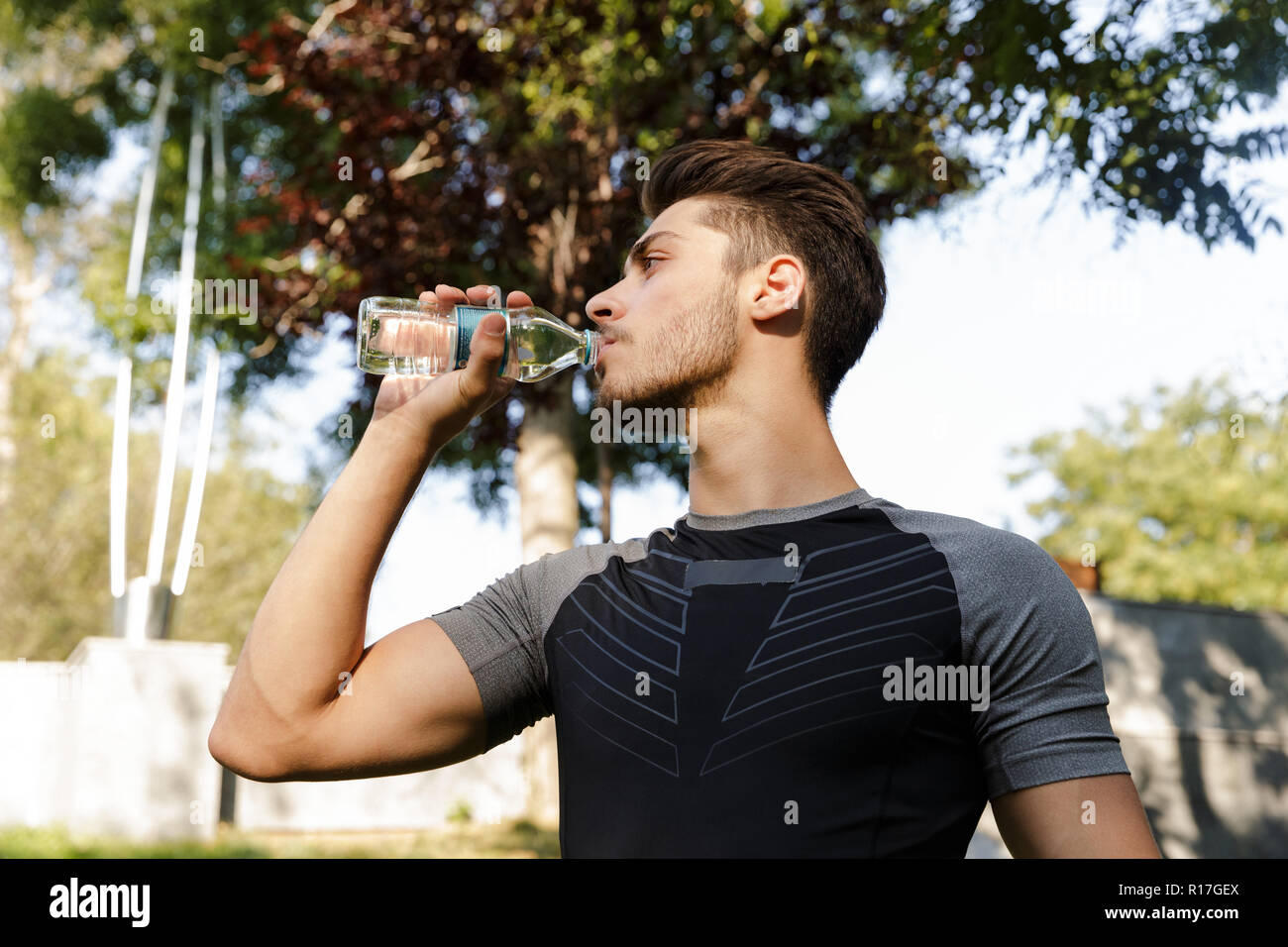 Image der Jungen konzentriert Sport Mann draußen im Park neben der Suche Trinkwasser. Stockfoto