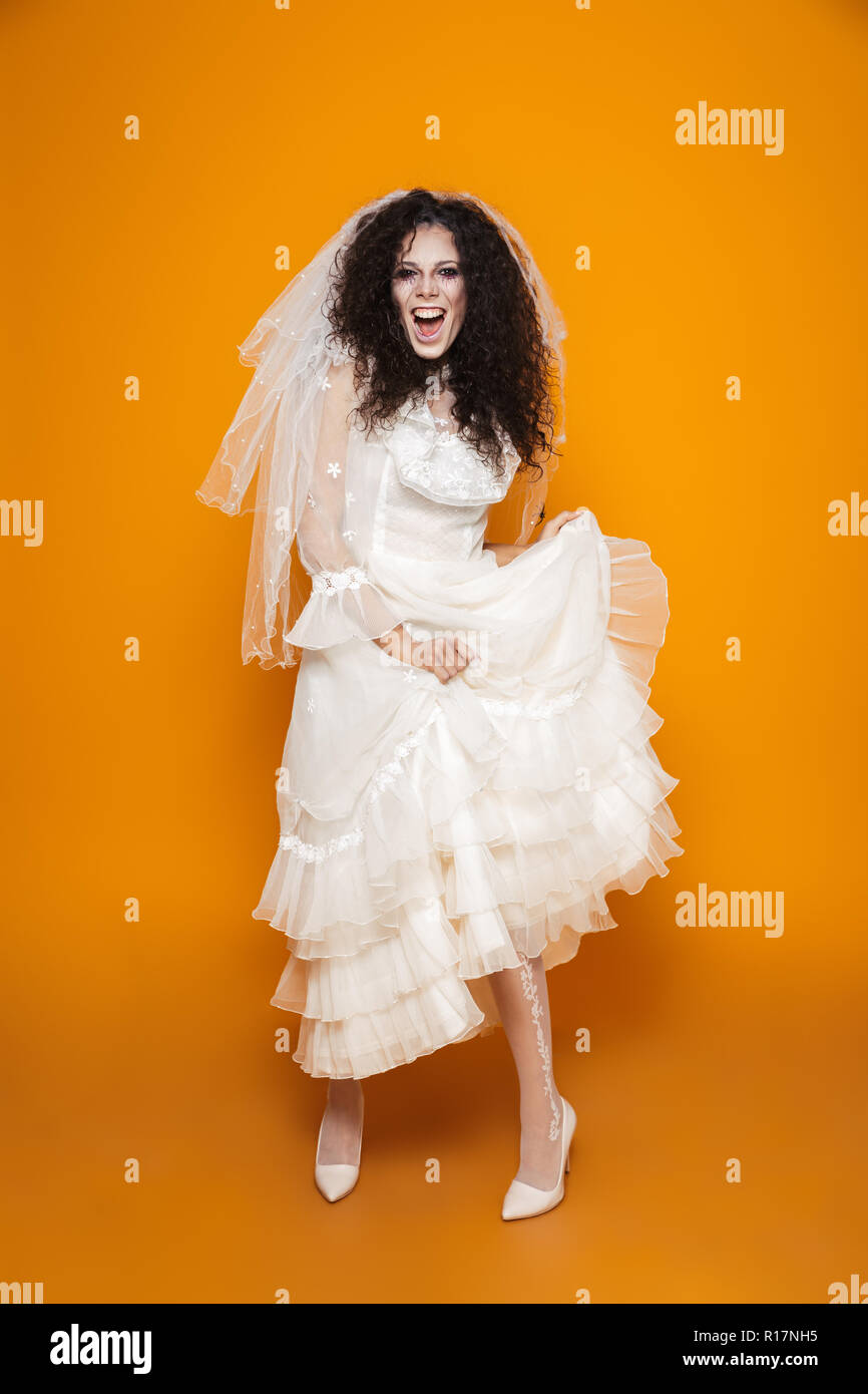 Volle Länge Image der Jungen zombie Frau auf Halloween Hochzeit Kleid tragen und Urlaub Make-up Lachen und Spaß über Gelb Hintergrund isoliert Stockfoto