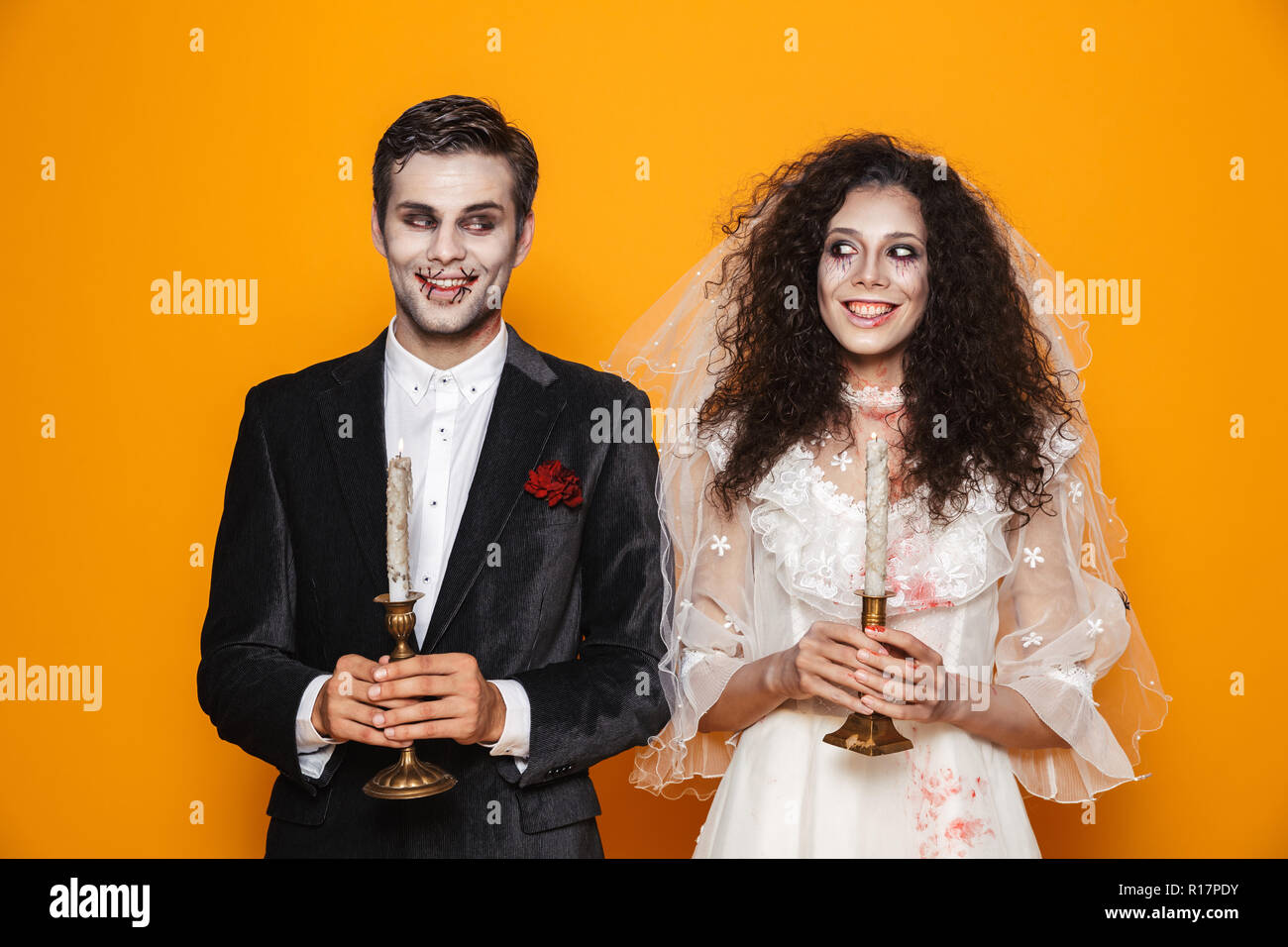 Glückliches Paar in Scary Haloween Kostüme auf gelben Hintergrund gekleidet Stockfoto