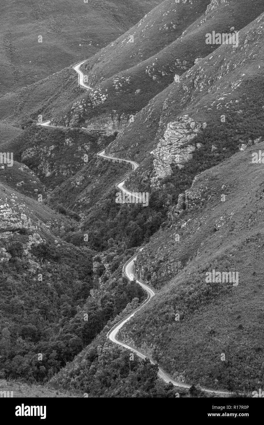 Hohe robuste Alte unbefestigte Straße durch schroffe Berge in schwarzen und weißen Landschaft. Stockfoto