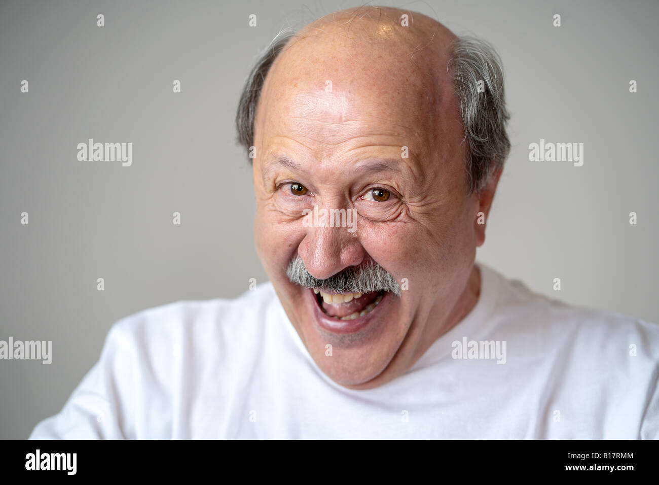 Lächeln und Lachen 60er Jahre alten älterer Mann candid Nahaufnahme portrait in menschliche Gefühle und Mimik Konzept in neutralen Hintergrund isoliert. Stockfoto
