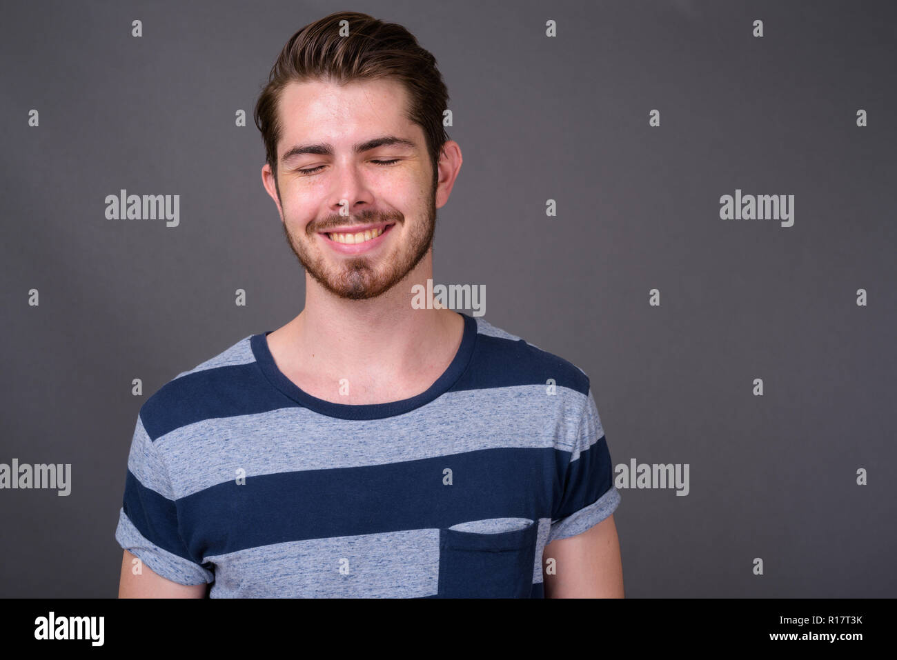 Die Jungen gut aussehenden bärtigen Mann gegen grauer Hintergrund Stockfoto