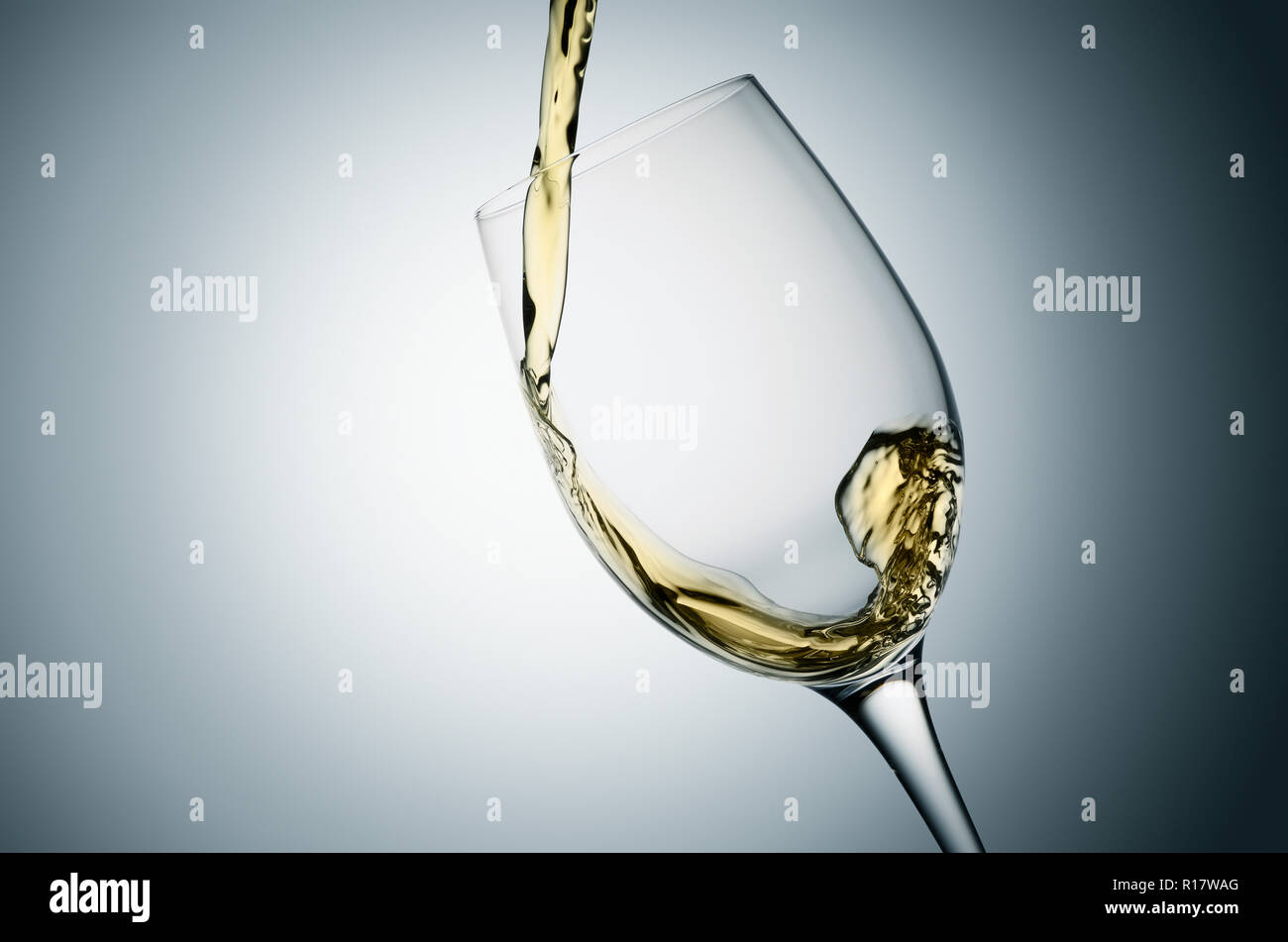 Gießen Weißwein in geneigten Glas, einfachen Hintergrund Stockfoto