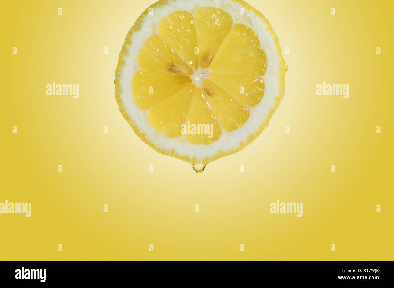 Nahaufnahme der Zitronenscheibe mit Tropfen Saft, gelber Hintergrund Stockfoto
